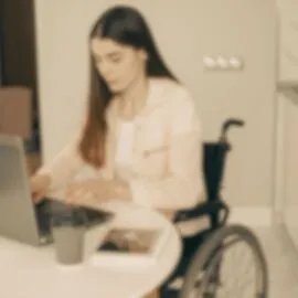 Image représentant une femme en fauteuil roulant qui utilise un ordinateur pour illustrer l'article : +20 outils pour t’aider dans la création de ton site éthique et éco-responsable