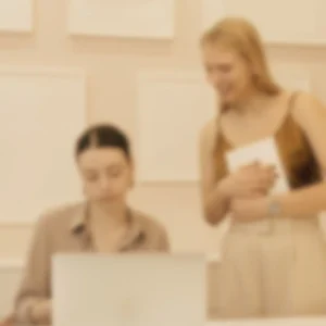 Image représentant 2 personnes une debout, une assisse, en train de regarder un écran d’ordinateur pour illustrer l'article : L’accessibilité : mon chemin de designer pour sortir du “beau” et viser le juste